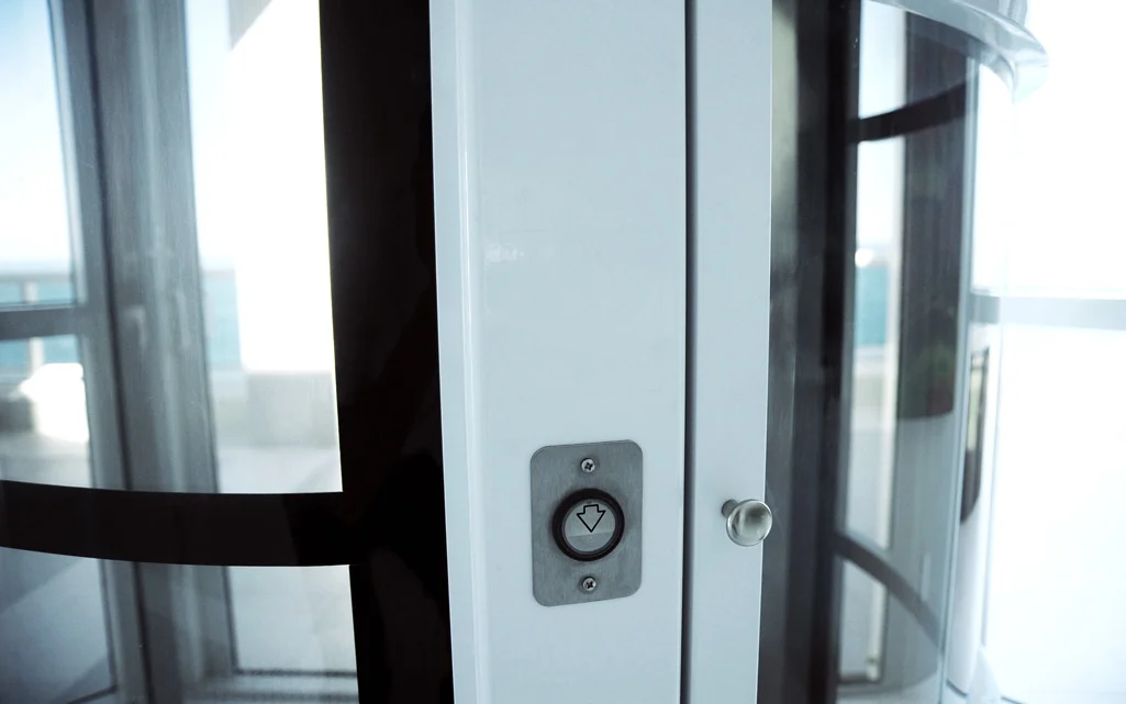 Newmatic-close-up Close-up of a modern glass lift with a minimalist design and a simple control button.